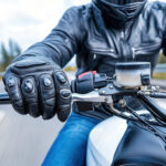 Rider in black leather jacket gripping motorcycle throttle, showcasing speed and control