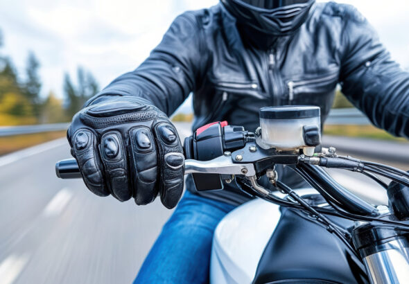 Rider in black leather jacket gripping motorcycle throttle, showcasing speed and control